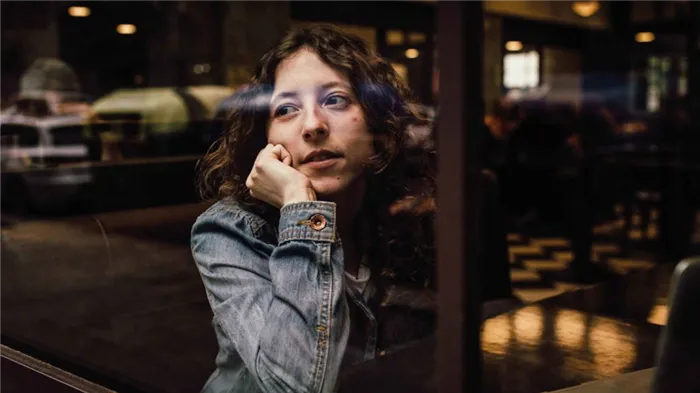 Девушка сидит в кафе и задумчиво смотрит на улицу