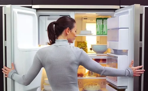 Девушка открыла чистый холодильник и смотрит
