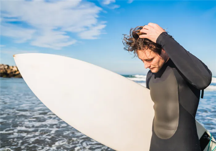 young-surfer-standing-in-the-ocean-with-his-surfboard-in-a-black-surfing-suit-sport-and-water-sport-concept (1).jpg